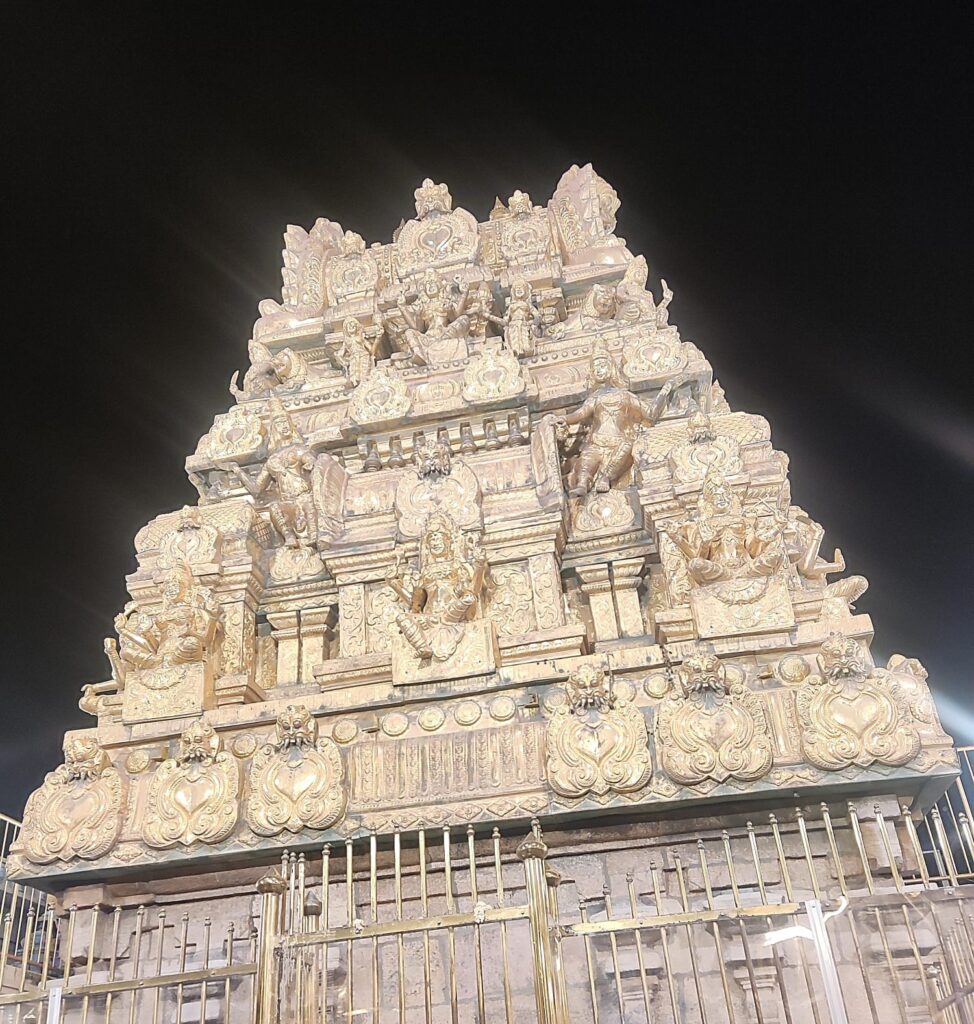 gold covered gopuram with intricate sculptural details at Samayapuram Mariamman Temple in Tamil Nadu, photographed at night.